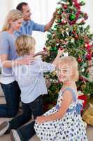 Family hanging decorations on a Christmas tree