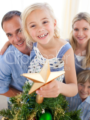 Father lifting his daughter to put the Christmas star on top of