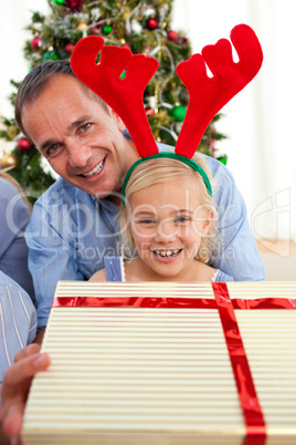 Portrait of a smiling father and his daughter opening Christmas