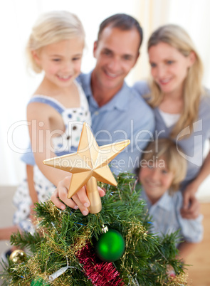 Father lifting his daughter to put the Christmas star on top of