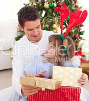 Portrait of a smiling father and his daughter opening Christmas