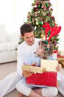 Smiling father and his daughter opening Christmas gifts