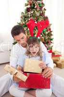 Surprised little girl opening presents with her father