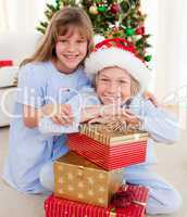 Smiling siblings holding Christmas gifts