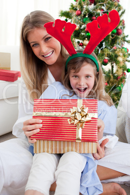 Smiling mother and her daughter opening Christmas gifts