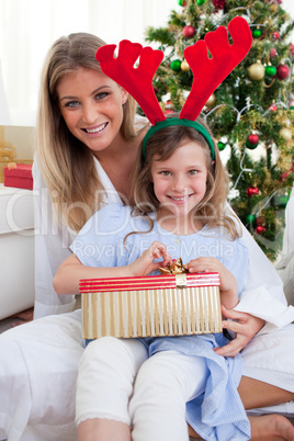 Smiling mother and her daughter unpacking Christmas gifts