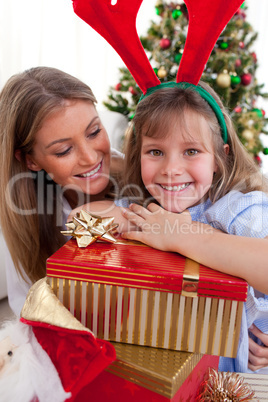 Smiling mother and her daughter holding Christmas gifts