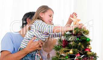 Little girl placing a star in a Christmas tree