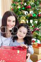 Mother and daughter at home holding a Christmas gift