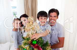 Happy little kid decorating a Christmas tree with his family