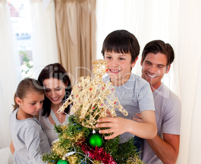 Smiling family decorating a Christmas tree at home