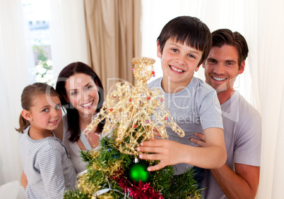 Happy little boy decorating a Christmas tree with his family