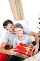 Smiling little girl with her father holding a Christmas gift