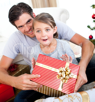 Happy little girl with her father receiving a Christmas present