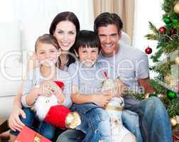 Portrait of a smiling family at Christmas time holding lots of p