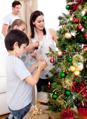 Happy children and parents decorating a Christmas tree