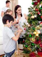 Happy children and parents decorating a Christmas tree