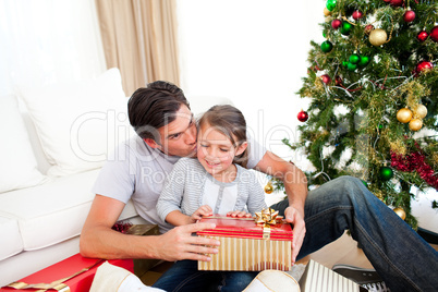 Father kissing his little daughter after giving her a Christmas