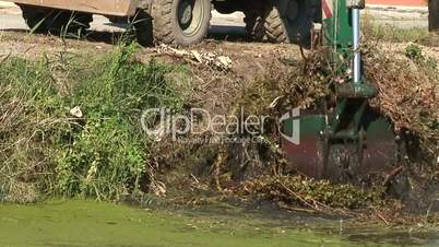 Removing silt and overgrown vegetation from a canal