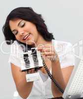 Ethnic businesswoman on phone and looking at an index holder
