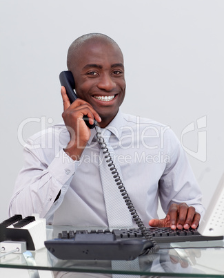 Smiling Afro-American businessman on phone in the office