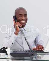 Smiling Afro-American businessman on phone in the office