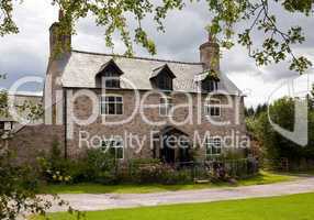 Old stone cottage surrounded by trees and roses