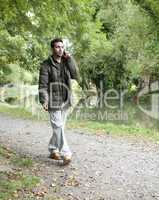 man on a mobile phone walking beside a canal or river