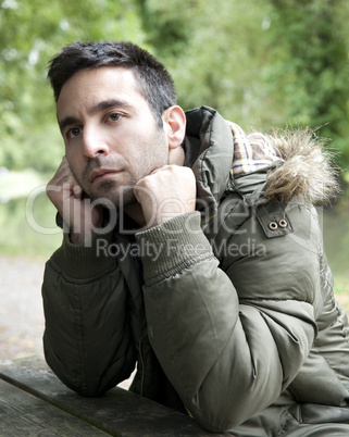 Man looking pensive, sitting by a canal.