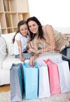 Smiling mother and her daughter opening shopping bags