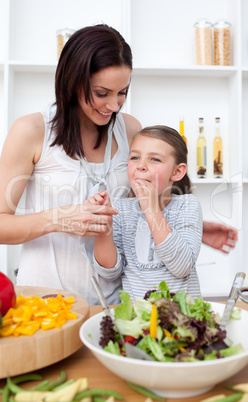 Little girl tasting salad with her mother
