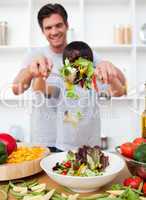 Happy father and his son preparing a salad