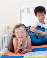 Close-up of a cute girl girl singing and her brother playing gui