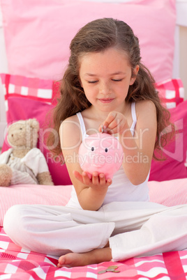 Smiling girl saving money in a piggybank