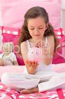 Smiling girl saving money in a piggybank