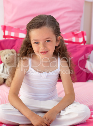 Little girl sitting on bed