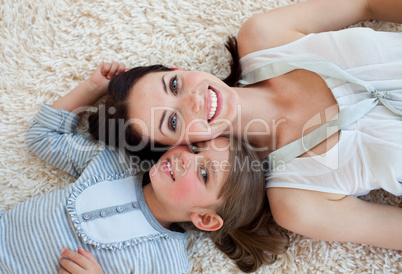 Happy little girl and her mother lying on the floor