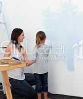 Mother and her daughter painting a wall together