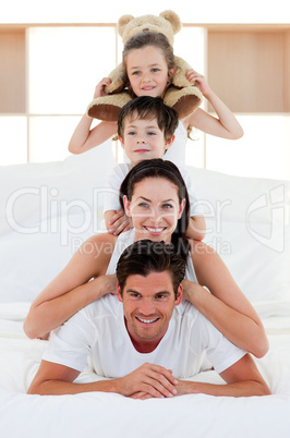 Parents and children playing on bed together