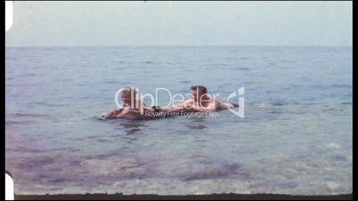 Vater und Sohn schwimmen auf einer Luftmatratze (8 mm-Film)