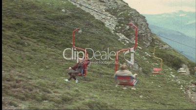Mann fährt mit dem Sessellift den Berg hinauf (8 mm-Film)