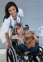 Little girl on a wheelchair holding her teddy bear