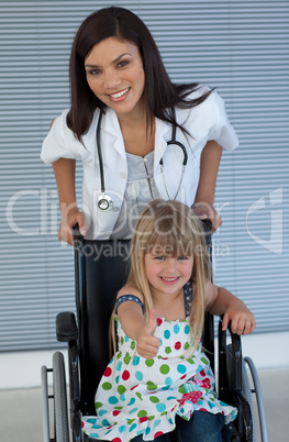 Young female doctor and Smiling girl on a wheelchair with thumb