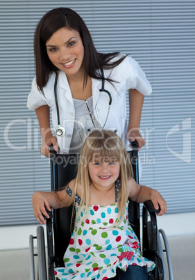 Portrait of a little girl on a wheelchair and a young doctor