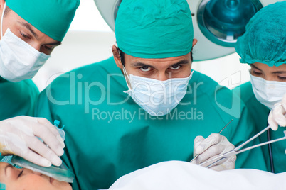 Multi-ethnic surgeons near patient lying on operating table