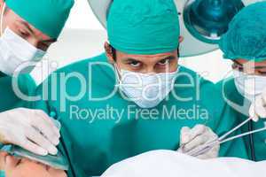 Multi-ethnic surgeons near patient lying on operating table