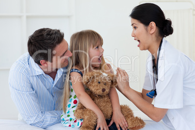 Little girl opening her mouth and the doctor checking her throat