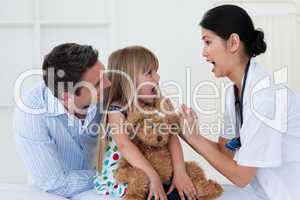 Little girl opening her mouth and the doctor checking her throat