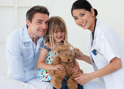 Portrait of a doctor and happy little girl examing a teddy bear