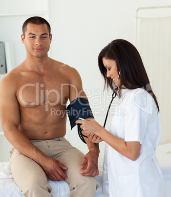 Smiling doctor checking the blood pressure of a patient